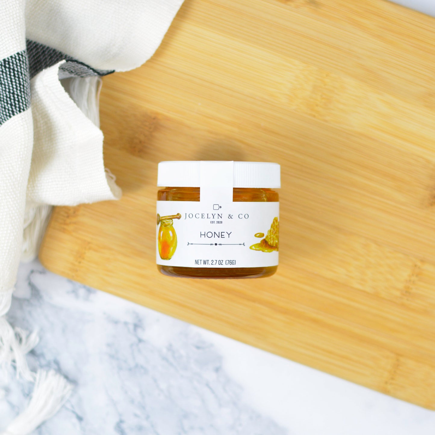 Jar of honey on a wooden cutting board with a marble background