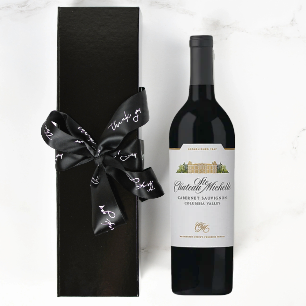 Chateau Ste. Michelle wine bottle with a black gift box and ribbon on a white background