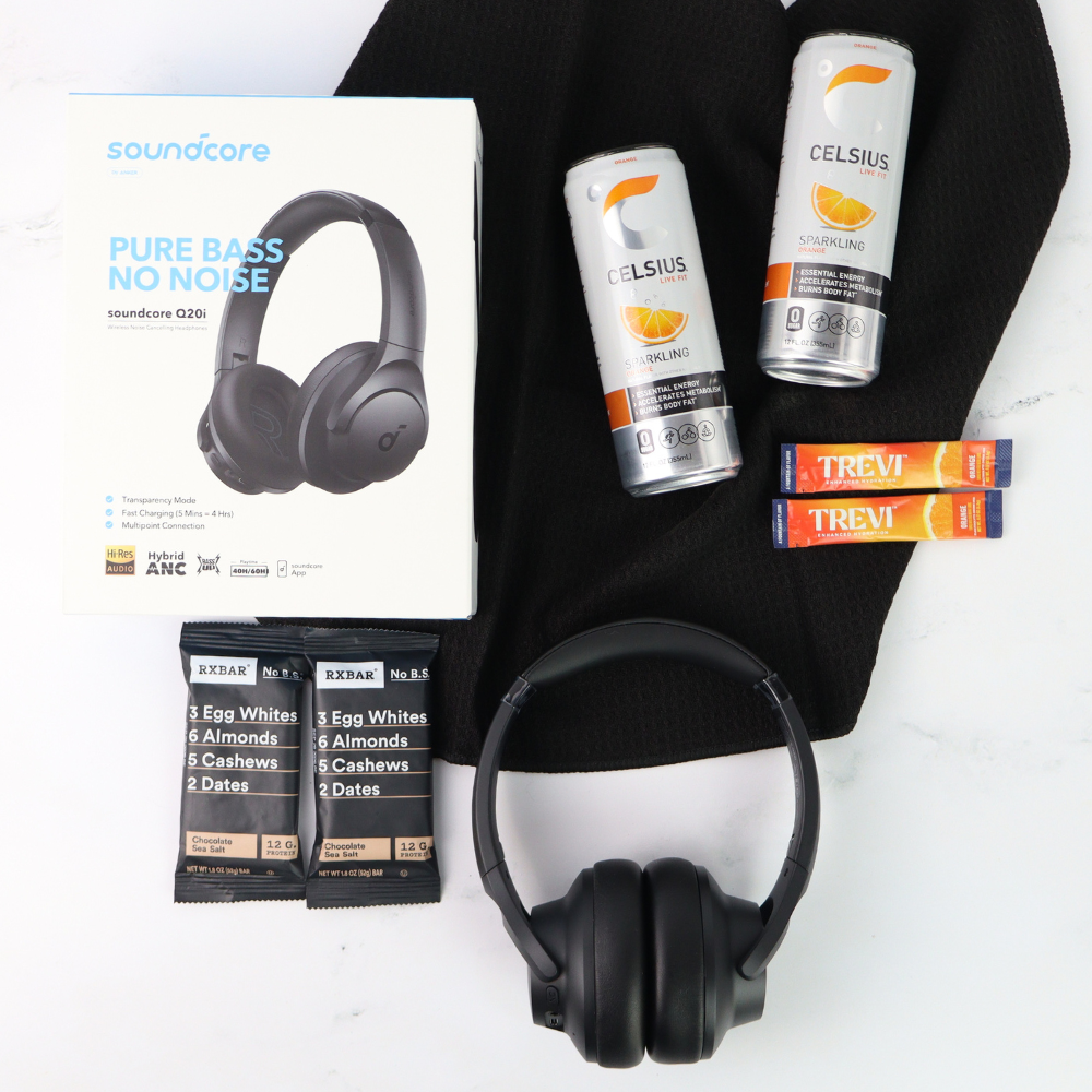 Black headphones, Celsius energy drink cans, and protein bars on a white background